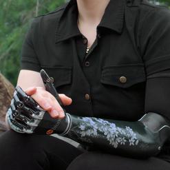 Junge Frau, die im Wald sitzt und eine Armprothese auf der linken Seite tr&auml;gt.