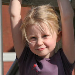 kleines M&auml;dchen, das an einem Ger&uuml;st h&auml;ngt